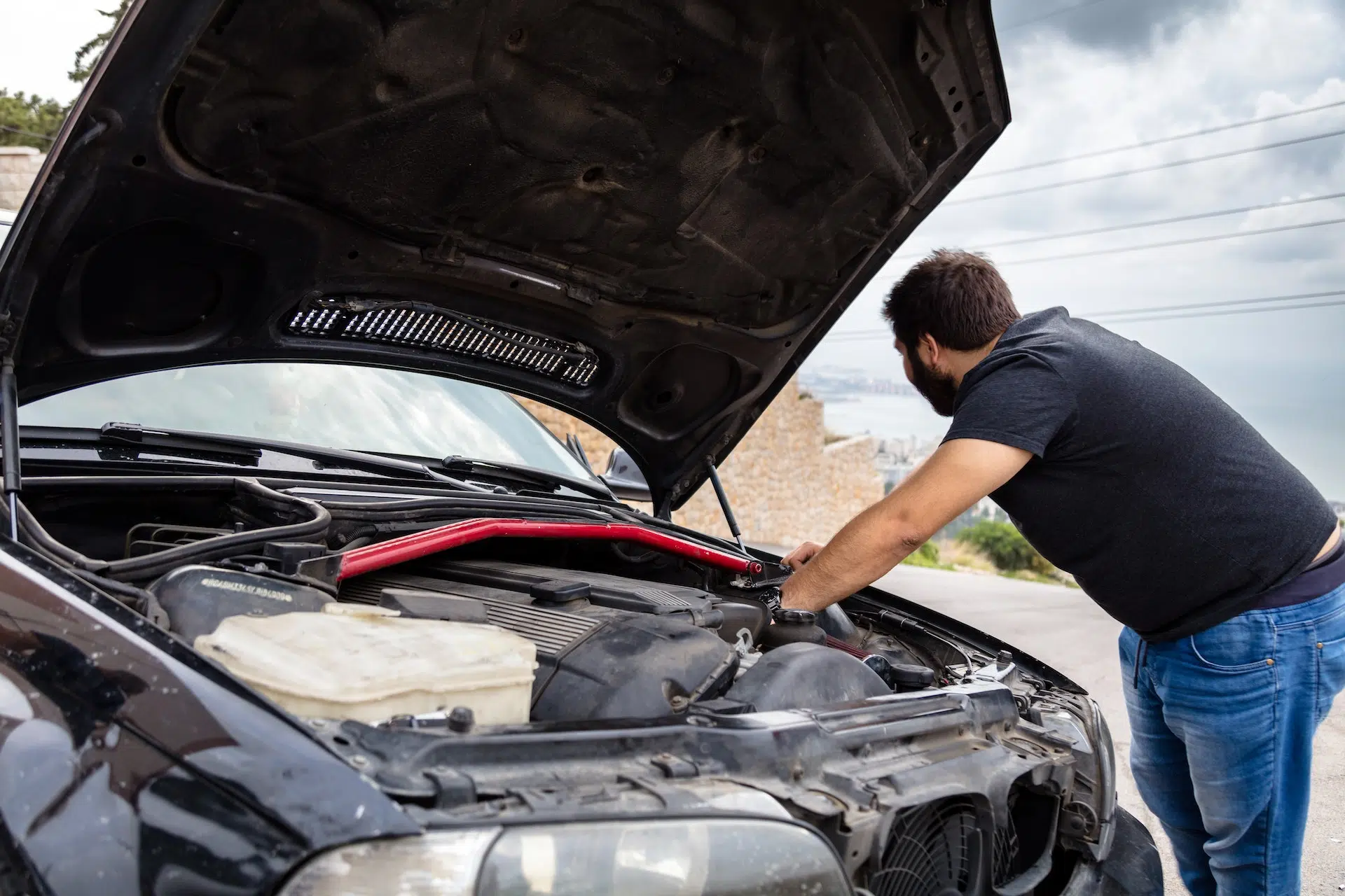 Dead Battery in the Georgia Heat: What To Do When Your Car Won't Start in Gwinnett County 4 Driver inspecting under car's hood | Statewide Wrecker